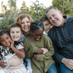 Joyful mixed-race family with four children hugging outdoors